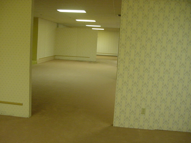 An slightly tiled image of a dingy looking, former furniture store, completely emptied of its contents.